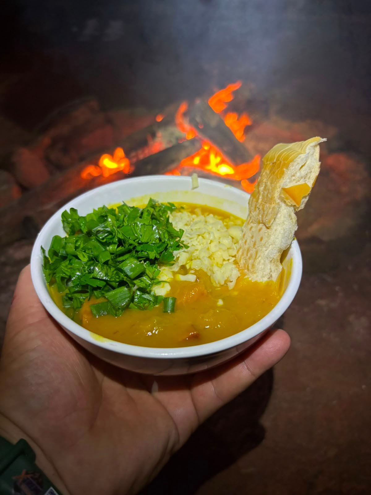 Caldo quente na caneca com fogueira ao fundo