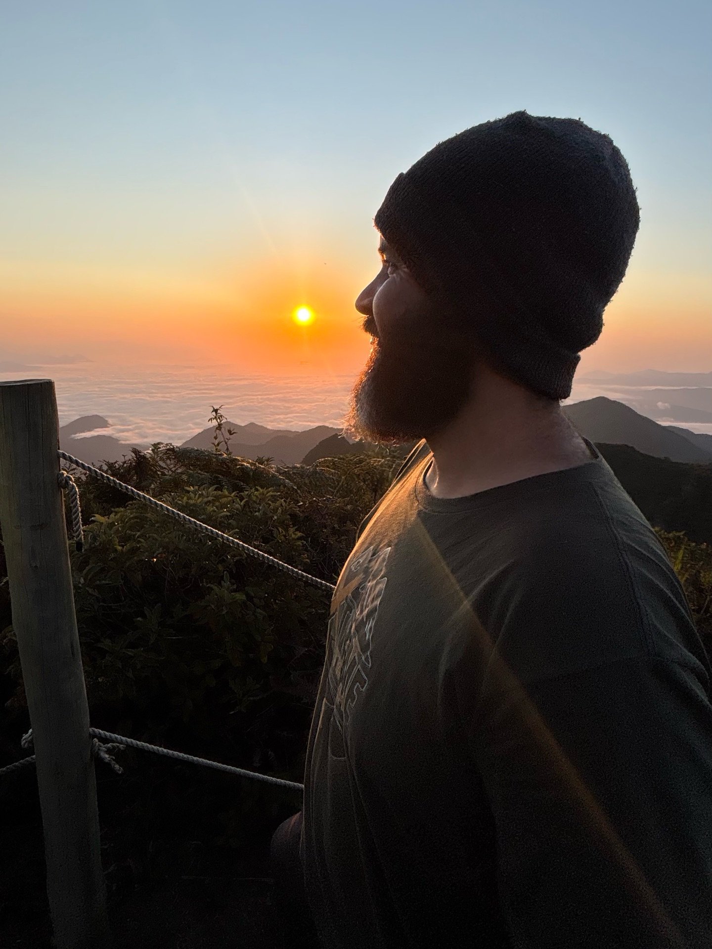 Participante em silhueta contemplando o nascer do sol sobre o mar de nuvens