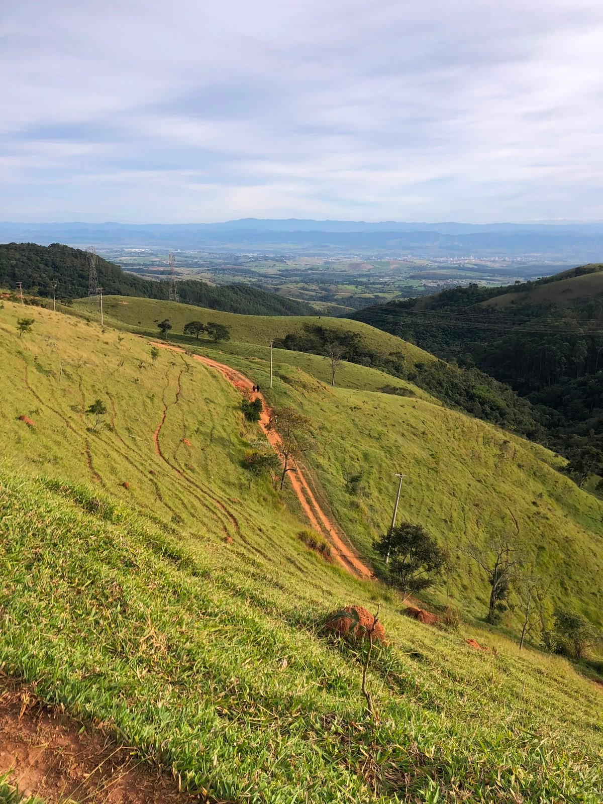 Vista da trilha de terra vermelha com o vale ao fundo